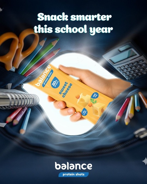 A high-angle shot looking into an open school backpack, showcasing a protein snack bar placed among school supplies like pencils and a calculator.